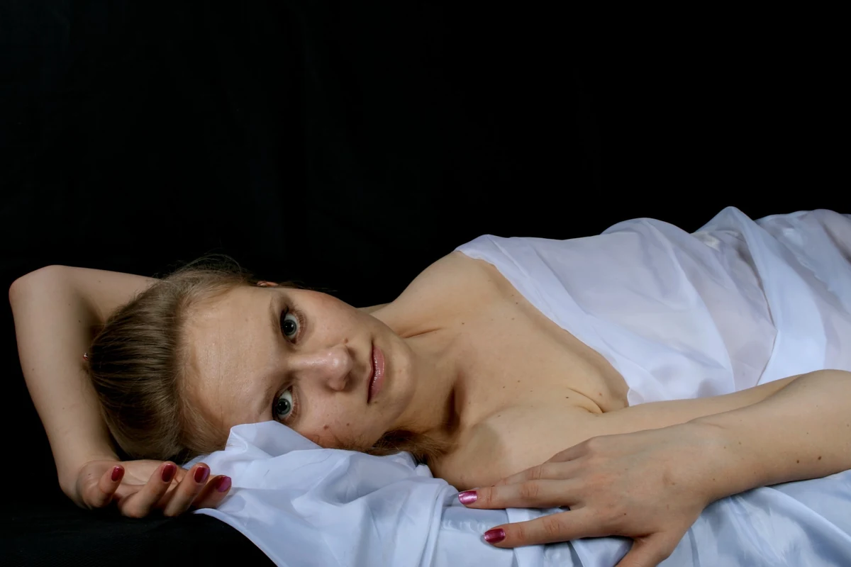 Reclining portrait on white fabric against a black backdrop