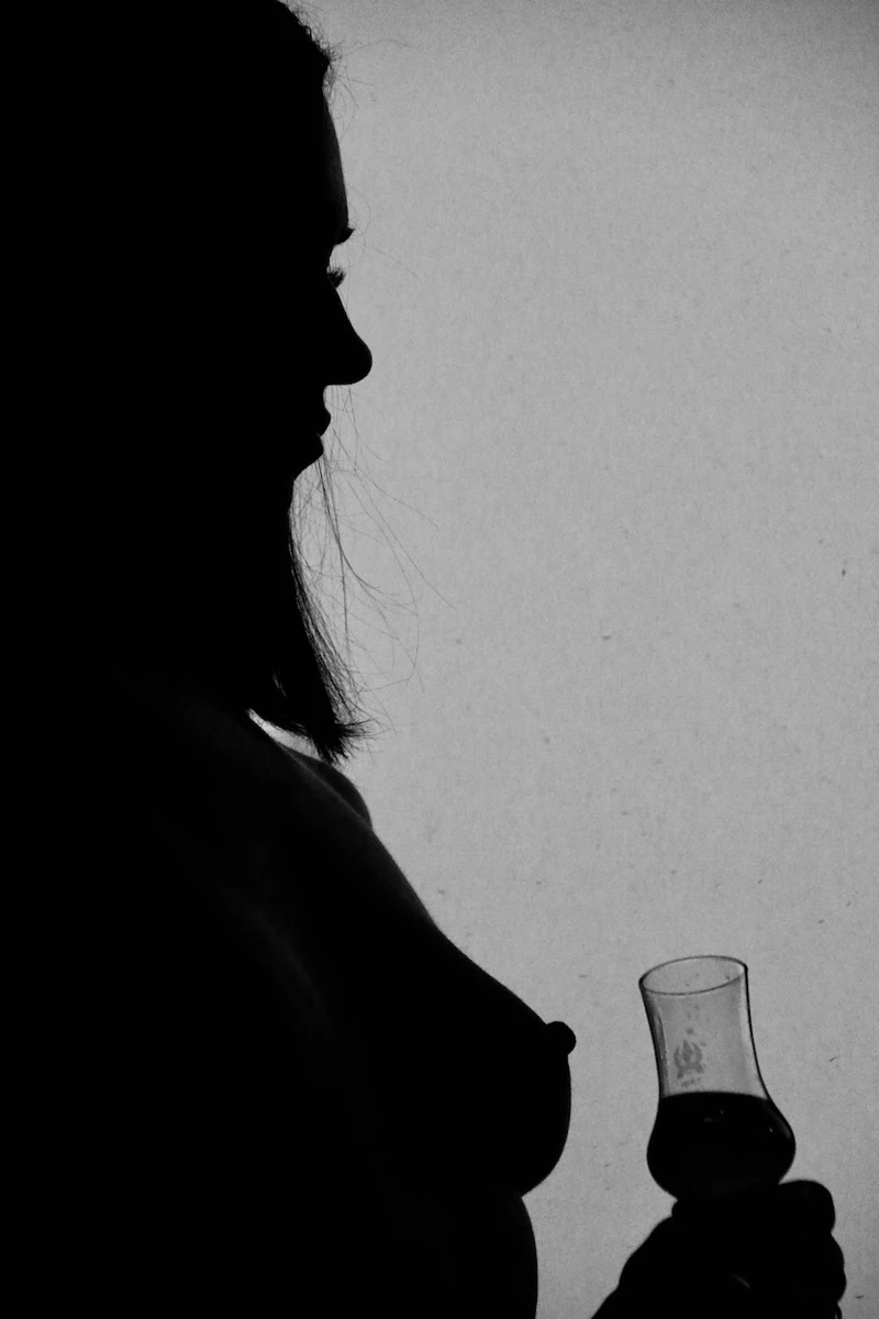 Black and white profile silhouette holding a small glass